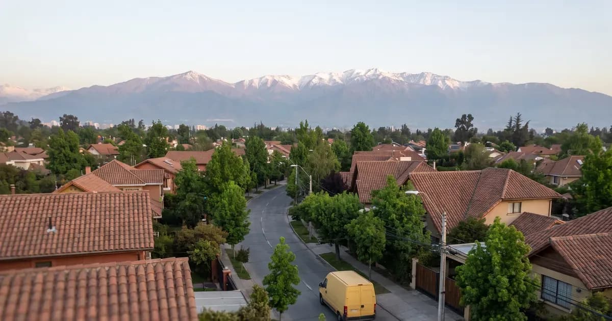 Vista aérea de un barrio de Santiago con un furgón escolar amarillo y la cordillera de fondo
